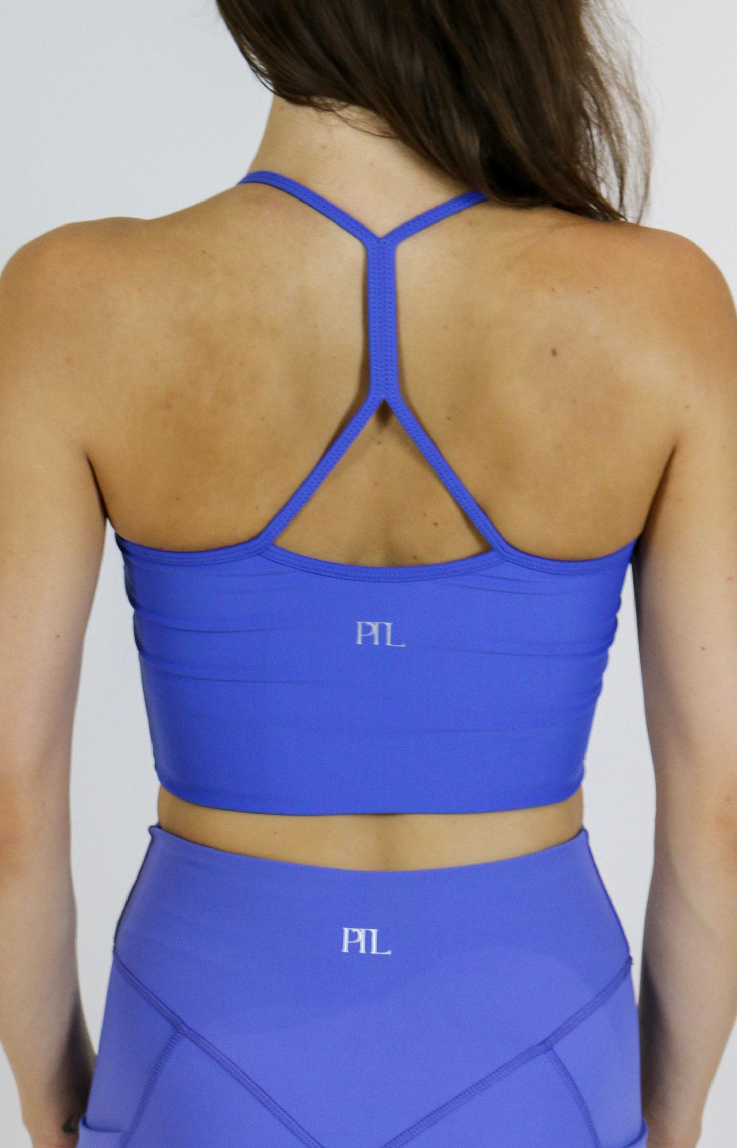 Person wearing a blue sports bra and leggings with 'PIL' branding on a plain background