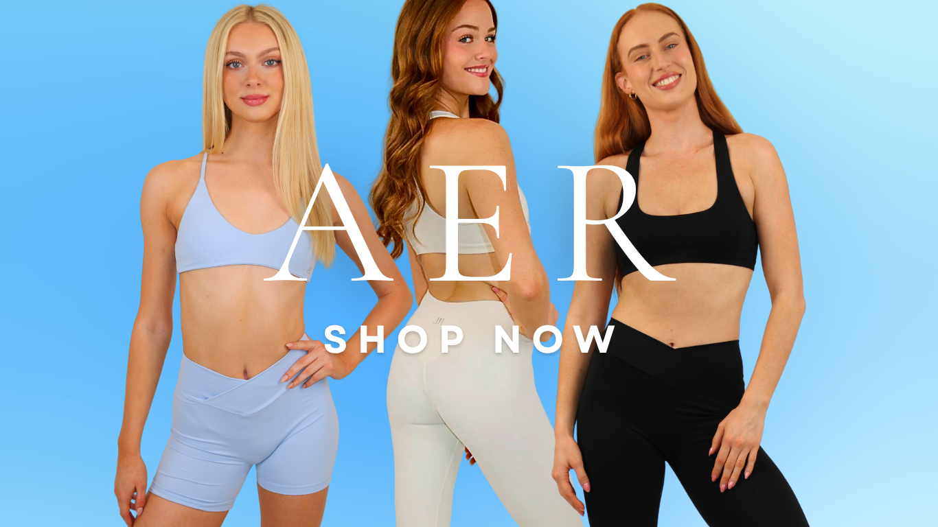 Three women modeling matching sports bra and leggings sets in light blue, beige, and black, with large white 'AER SHOP NOW' text overlaid on a light blue gradient background.