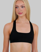 A blonde woman wearing a black square scoop-neck sports bra, shown from the chest up against a solid light gray background.