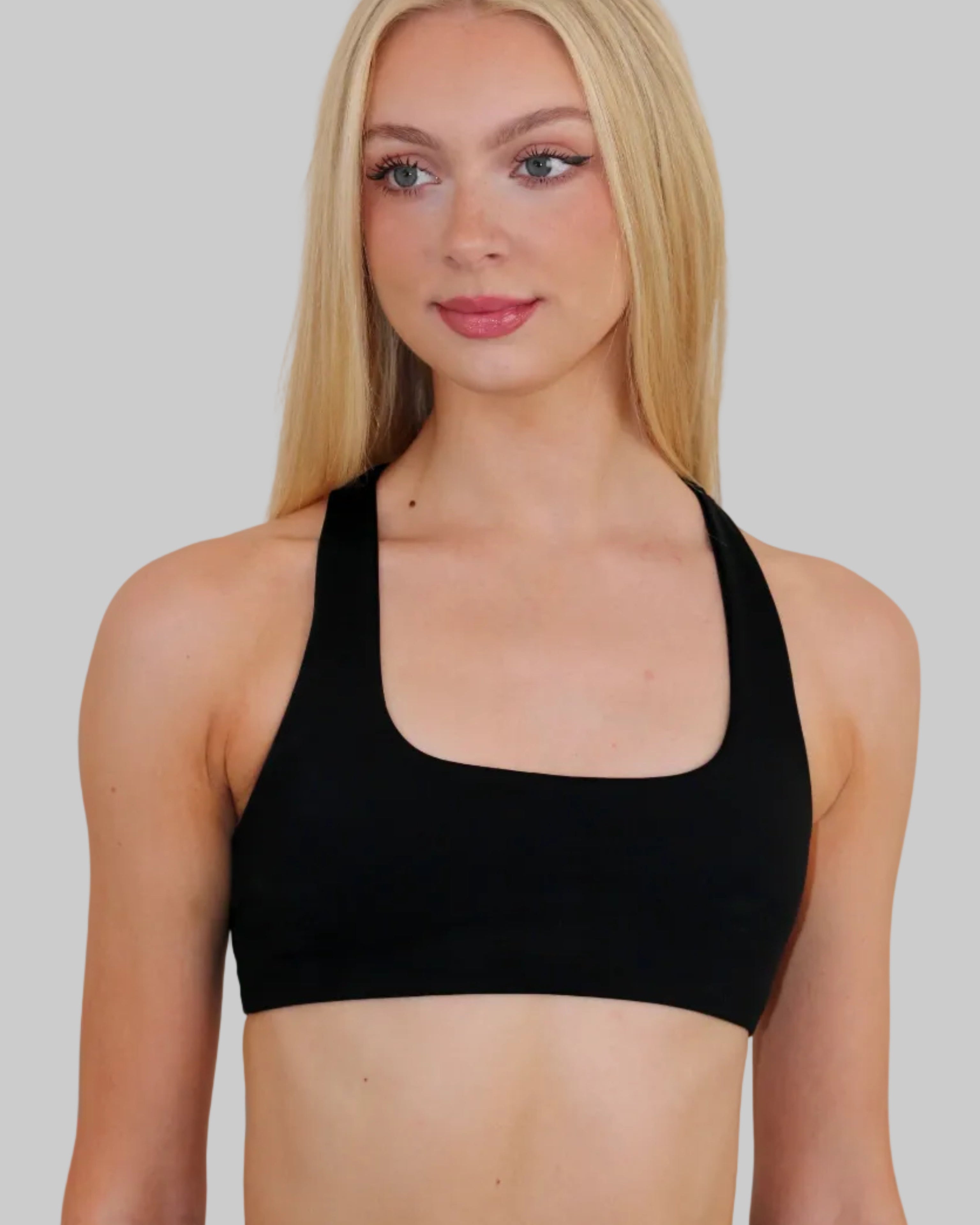 A blonde woman wearing a black square scoop-neck sports bra, shown from the chest up against a solid light gray background.